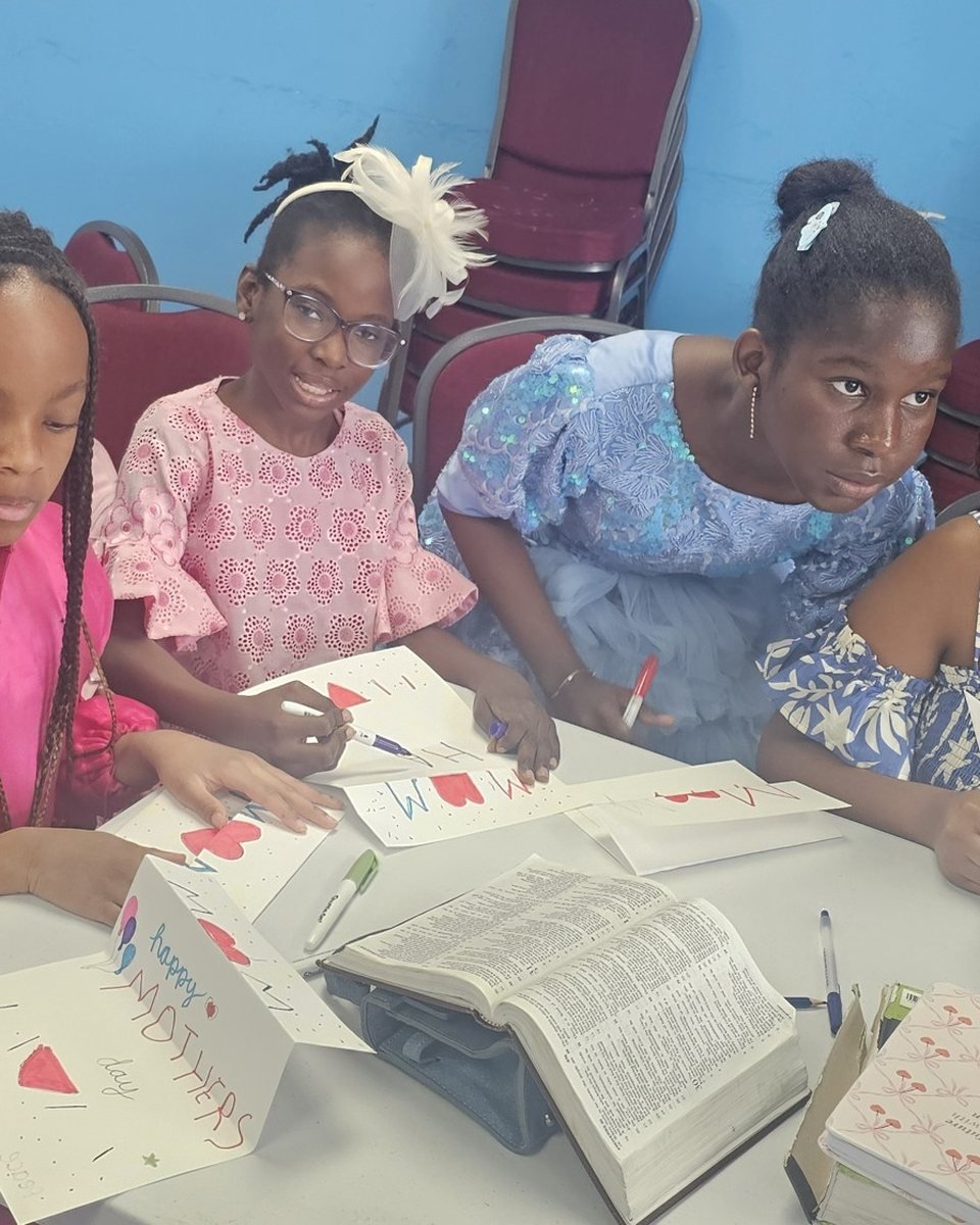 Girls in a Genesis class smiling over their open Bibles and worksheets